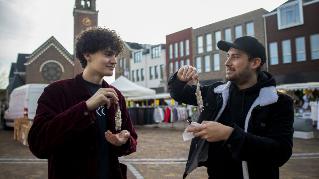 Two guys eating Dutch herring at local market in Moerdijk