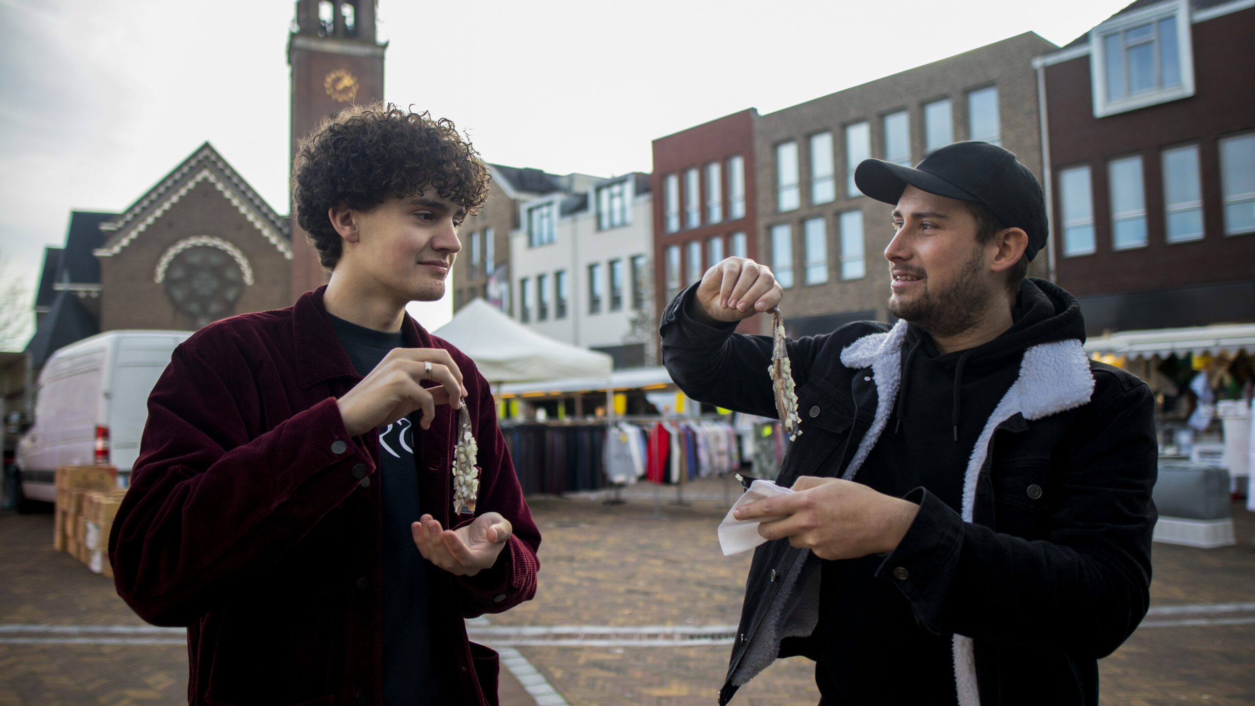 two guys having a herring with onions on market