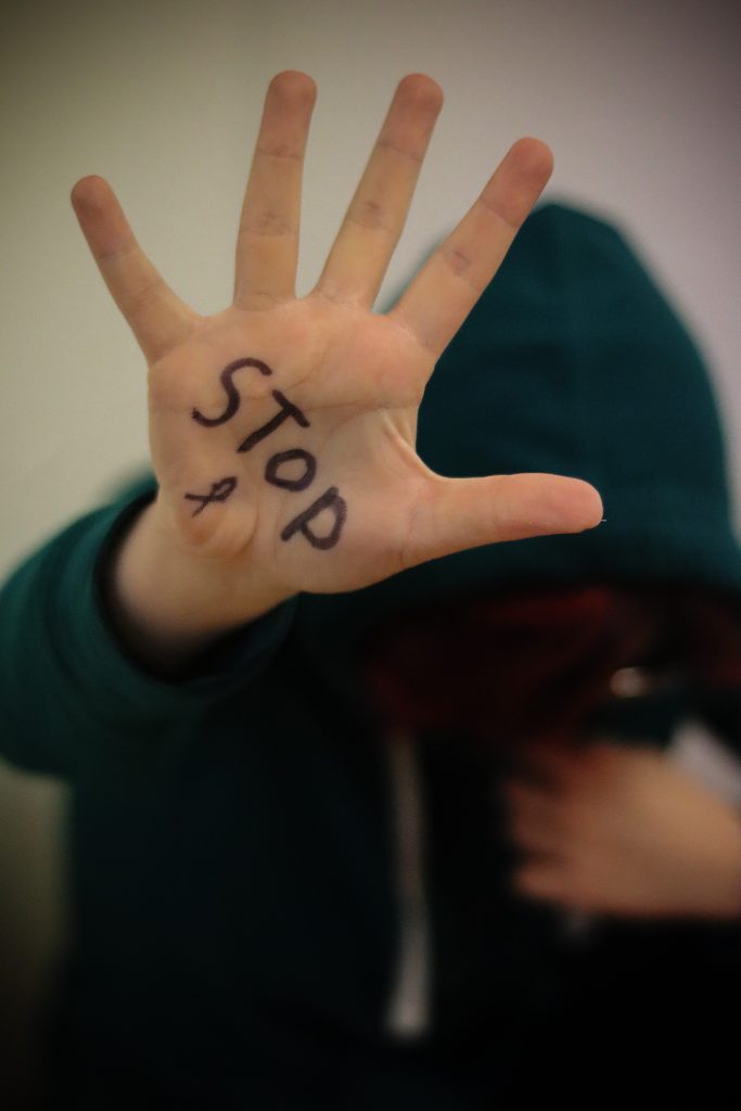 Girl sitting down with stop violence on her hand