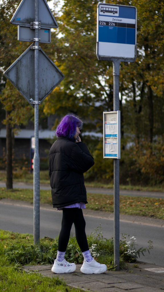 Girl with purple hair doubts at bus stop