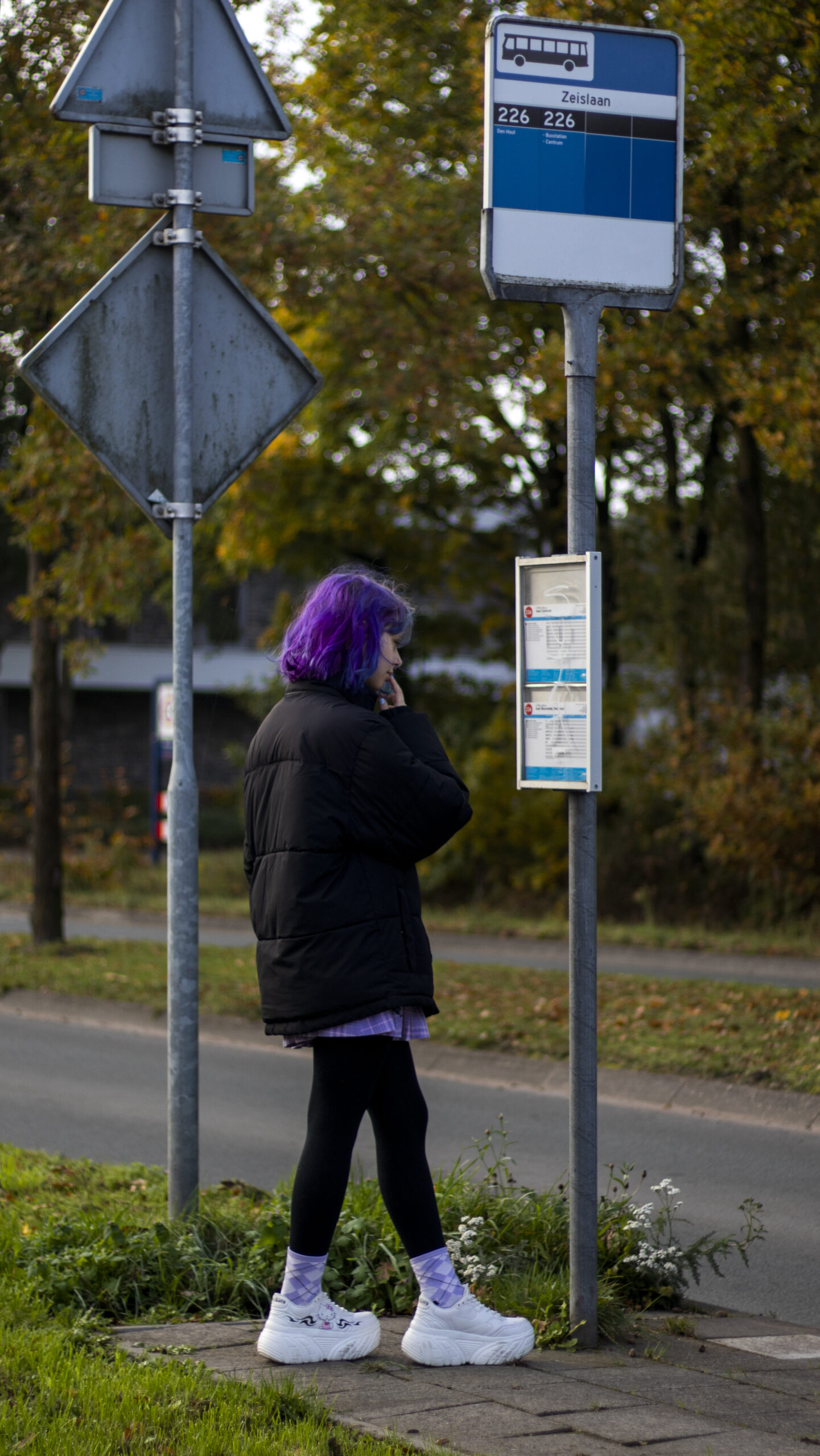 girl purple hair looking at bus stop