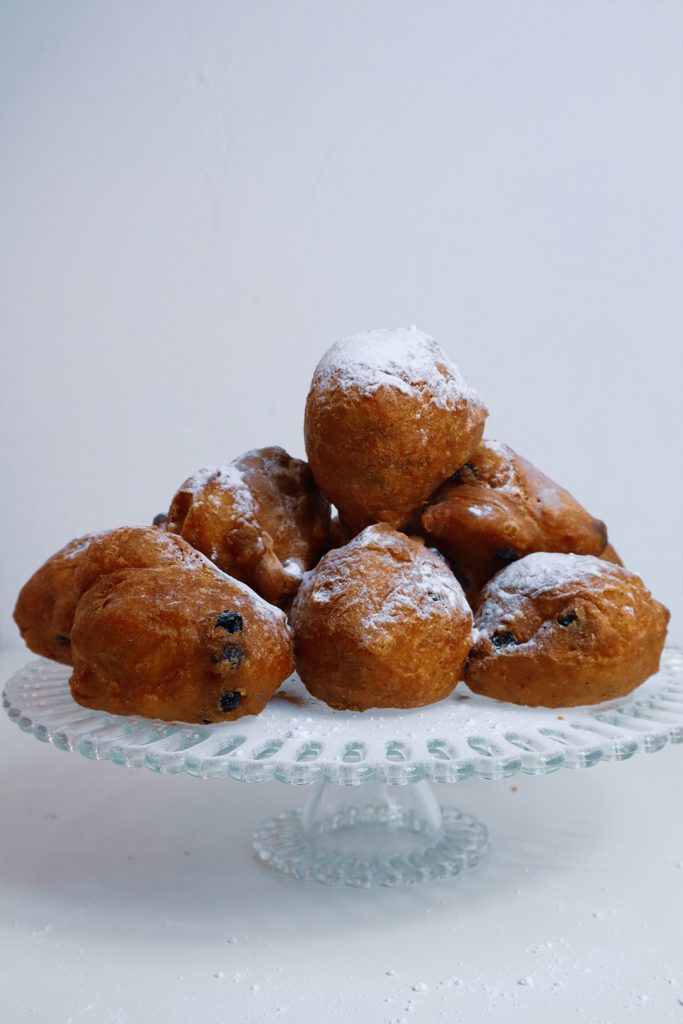 Stack of oliebollen on a serving platter with powdered sugar