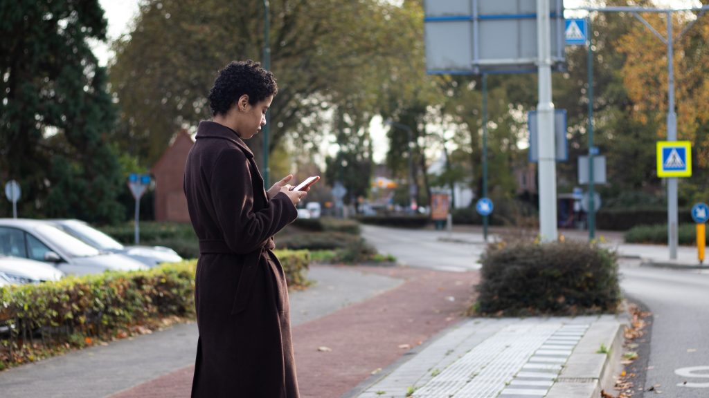 Young woman using public bus app at bus stop