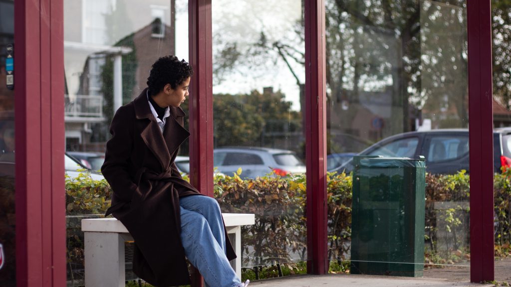 Young woman waiting for bus in bus stop shelter