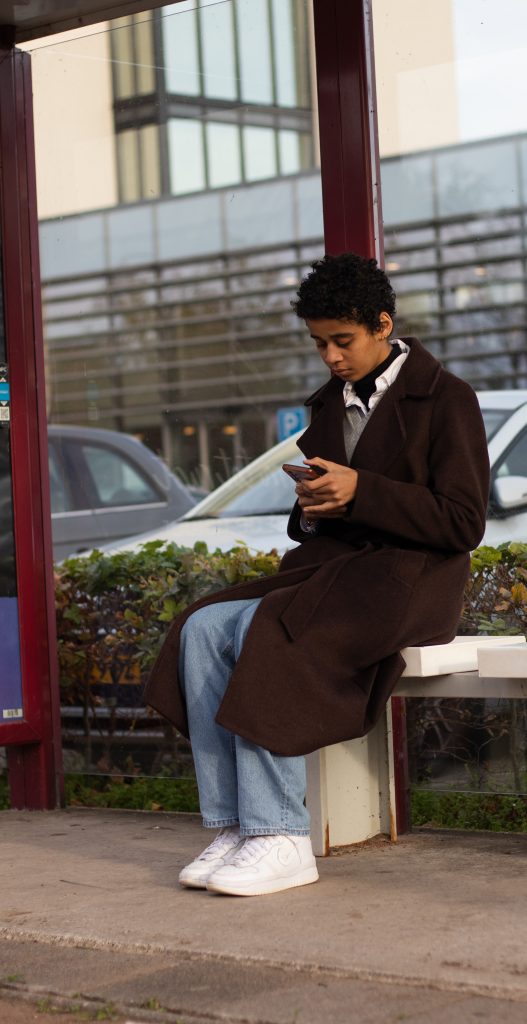 Young woman checking app while waiting on bus